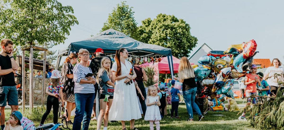 A lively outdoor gathering with families enjoying balloons and a sunny day.