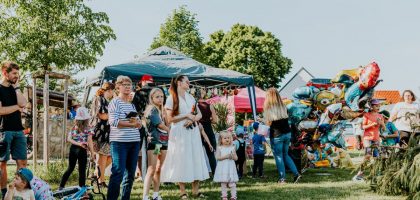 A lively outdoor gathering with families enjoying balloons and a sunny day.