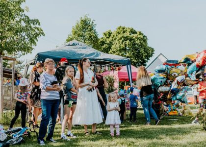 A lively outdoor gathering with families enjoying balloons and a sunny day.